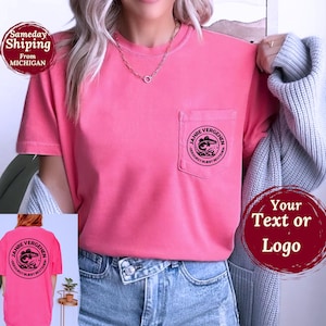 May include: A coral-colored t-shirt with a pocket featuring a black circular graphic with text and a fish design. The shirt has short sleeves and is worn with blue jeans. The text on the graphic reads "JAHRE VERGEHEN DERDURST BLEIBT BESTEHEN."