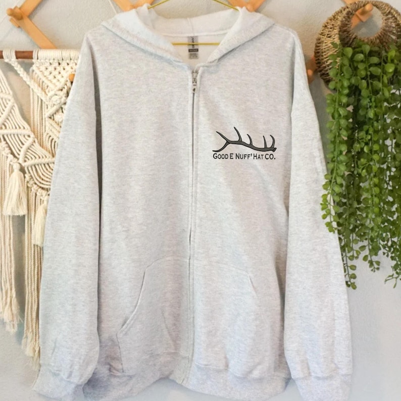 May include: A gray zip-up hoodie with a black embroidered antler design and the text "Goode Nuff Hat Co."