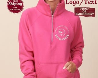 Può includere: Una felpa rosa acceso con mezza zip e una grafica bianca sul petto sinistro che raffigura la sagoma di una testa umana con un'onda sonora all'interno e il testo Speech Therapy Center of Excellence.