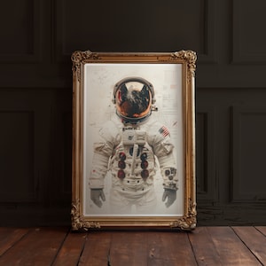 May include: A framed print of an astronaut in a white spacesuit with a red, white, and blue American flag patch on the arm. The astronaut is wearing a helmet with a reflective visor. The print is in a gold frame.