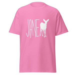 Puede incluir: Camiseta rosa con una silueta blanca de un ciervo y la palabra "JANE" impresa en la parte delantera.