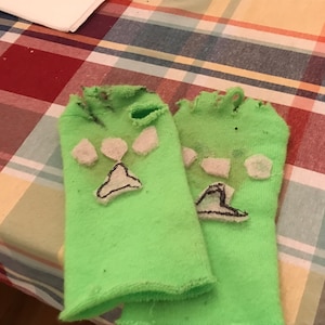 May include: A pair of green socks with paw print designs. The socks are worn and have holes in them.