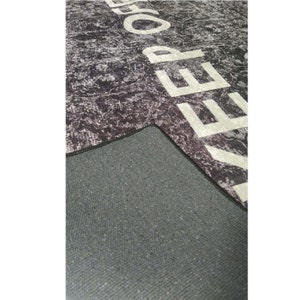 May include: A black and white rug with the word "KEEP" printed in white on the surface. The rug has a black backing.