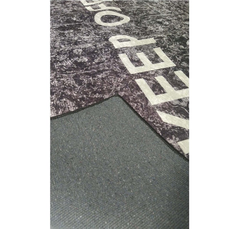 May include: A black and white rug with the word "KEEP" printed in white on the surface. The rug has a black backing.