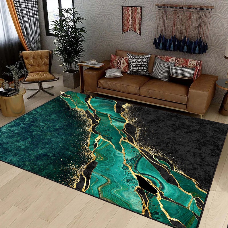 Puede incluir: Una alfombra de &aacute;rea abstracta verde y dorada con un dise&ntilde;o marmoleado. La alfombra tiene un fondo negro con vetas doradas y remolinos verdes.