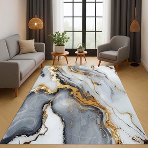 Può includere: Un tappeto rettangolare con un design marmorizzato. Il tappeto presenta una base bianca con venature grigie e dorate. Gli accenti dorati creano un aspetto lussuoso. Il tappeto è in un salotto.