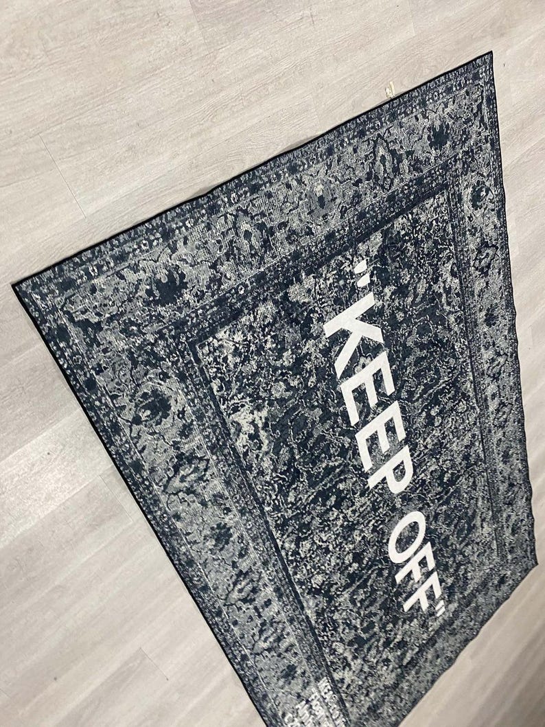 May include: A black and white rug with a vintage design and the text "KEEP OFF" in white lettering.