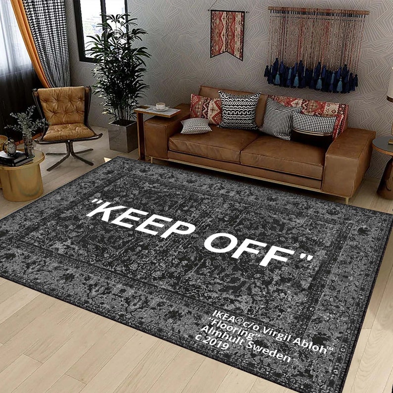 May include: A black and gray area rug with a white "KEEP OFF" text design. The rug has a vintage, distressed look and features the IKEA logo and designer Virgil Abloh's name.