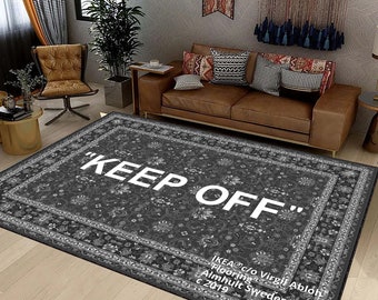 May include: A black and white patterned rug with the text "KEEP OFF" in white lettering. The rug has a border with a floral design. The text "IKEA c/o Virgil Abloh Flooring Almhult Sweden © 2019" is printed in white in the bottom right corner.