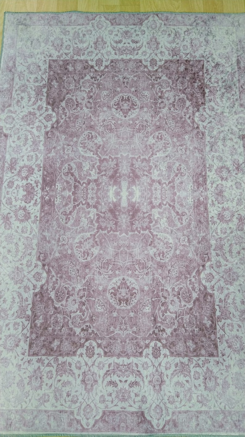 May include: A vintage-style rug with a floral pattern in shades of pink and white. The rug has a faded, distressed look, giving it a unique and antique feel.