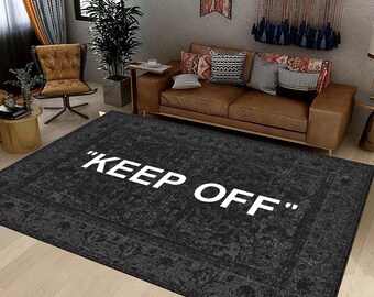 May include: A black and grey area rug with a white "KEEP OFF" text printed on it. The rug has a distressed, vintage look.