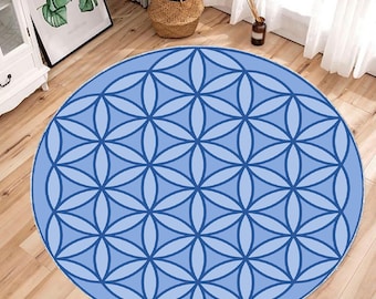 Op de afbeelding: Een rond blauw en wit geometrisch patroon tapijt met een levensbloem ontwerp.