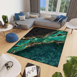 Puede incluir: Una alfombra de &aacute;rea abstracta verde y dorada con un dise&ntilde;o marmoleado. La alfombra tiene un fondo negro con acentos dorados y remolinos verdes.
