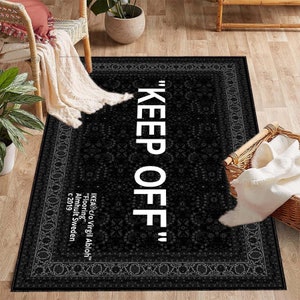 K&ouml;nnte beinhalten: Schwarz-wei&szlig;er Teppich mit traditionellem Muster an der Kante. Der Teppich tr&auml;gt den Schriftzug "KEEP OFF" in wei&szlig;en Buchstaben.
