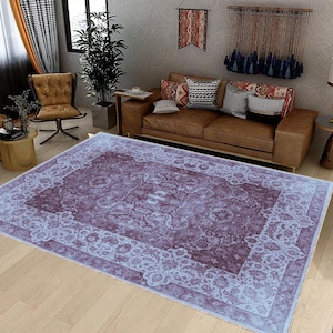 May include: A light blue and purple patterned area rug with a floral design. The rug is laid out on a wooden floor in a living room setting.
