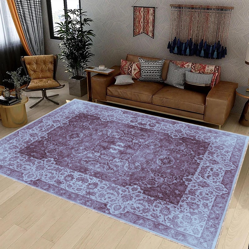 May include: A light blue and purple patterned area rug with a floral design. The rug is laid out on a wooden floor in a living room setting.