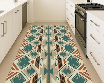 May include: A rectangular kitchen rug with a geometric pattern in teal, brown, beige, and black. The rug features a symmetrical design with triangles, diamonds, and other shapes. The rug is placed in a kitchen with white cabinets and appliances.