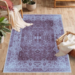 May include: A light blue and purple patterned area rug with a floral design. The rug has a border with a repeating pattern.