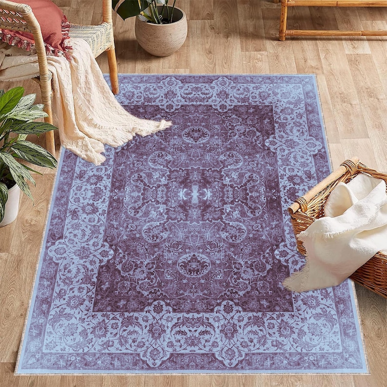 May include: A light blue and purple patterned area rug with a floral design. The rug has a border with a repeating pattern.