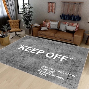 Könnte beinhalten: Ein grauer und weißer Teppich mit Muster und dem Text "KEEP OFF" in weißen Buchstaben. Der Teppich enthält auch den Text "IKEA®c/o Virgil Abloh™" "Flooring" "Almhult Sweden" "c 2019".