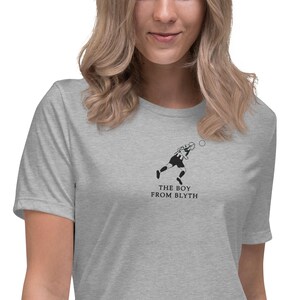 May include: A grey t-shirt with a black and white graphic of a footballer kicking a ball. The text "THE BOY FROM BLYTH" is printed beneath the image.