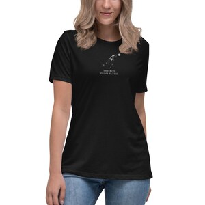 May include: Black t-shirt featuring a white graphic of a person throwing a ball, with the text "THE BOY FROM BLYTH" in white. The shirt has a relaxed fit and is being worn.