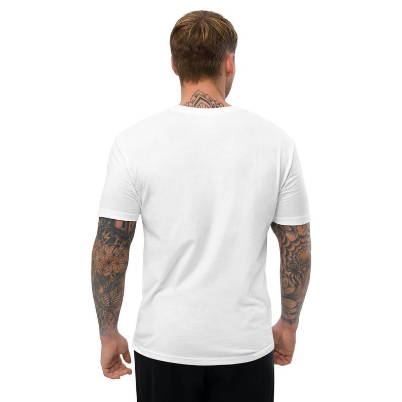 K&ouml;nnte beinhalten: Ein schlichtes, wei&szlig;es T-Shirt mit kurzen &Auml;rmeln. Das Shirt besteht aus einem weichen Material und hat einen Rundhalsausschnitt. Die R&uuml;ckseite des Shirts ist sichtbar, und die Person, die das Shirt tr&auml;gt, hat T&auml;towierungen an Armen und Hals.