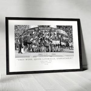 Op de afbeelding: Zwart-wit ingelijste afdruk met een voetbalteam dat een overwinning viert. De tekst "BARCLAYCARD CHAMPIONS" en de jaren 2003-2004 zijn zichtbaar. De quote "THEY WERE, QUITE LITERALLY, UNBEATABLE!" is ook aanwezig.