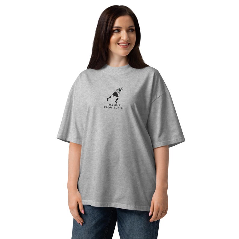 May include: A gray oversized t-shirt with a black graphic of a person running and the text "THE BOY FROM BLYTH". The shirt is made of a soft material and has short sleeves.