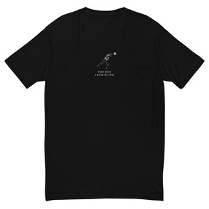 K&ouml;nnte beinhalten: Schwarzes T-Shirt mit einer kleinen wei&szlig;en Grafik eines Footballspielers, der einen Ball wirft. Unter der Grafik steht in Wei&szlig; der Text "THE BOY FROM BLYTH". Das Shirt hat kurze &Auml;rmel und einen Rundhalsausschnitt.