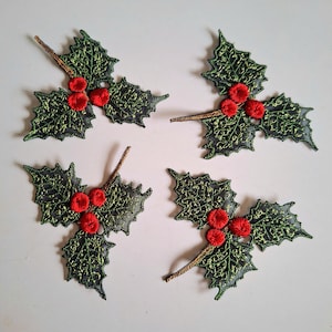 May include: Four holly leaf and berry embroidered patches. Each patch features three bright red circular berries and dark green leaves with intricate gold-toned thread detailing. The leaves have a jagged, pointed edge design and a sheer texture.
