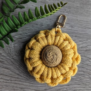 May include: A yellow crocheted sunflower keyring with a brown centre. The keyring has a gold metal ring.