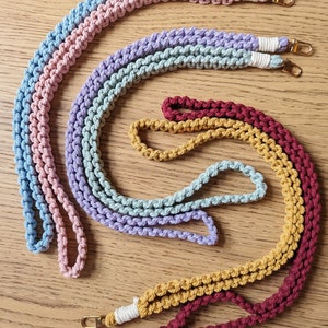 May include: Four crocheted cords in different colors: light pink, light blue, lavender, and burgundy. Each cord has a gold metal clasp at each end.