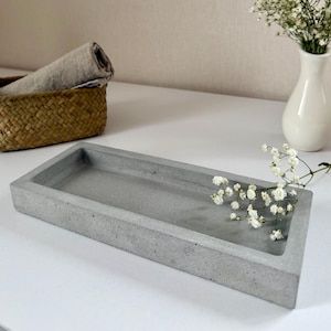 May include: A rectangular grey concrete tray with a rough texture. The tray is empty and has a slightly raised edge.