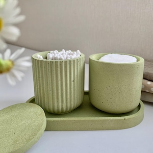 Op de afbeelding: Een set van drie keramische mokken met een gespikkelde, crèmekleurige glazuur. Elke mok heeft een handgeschilderd bloemmotief in blauw, groen en geel. De mokken hebben een eenvoudige, afgeronde vorm en een handvat.