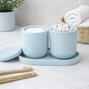 Op de afbeelding: Een set van drie keramische mokken met een gespikkelde, matte afwerking. De mokken zijn in crème, lichtgrijs en donkergrijs. Elke mok heeft een eenvoudig, minimalistisch ontwerp.
