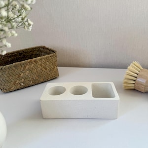 May include: White ceramic dish with three compartments, two round and one rectangular, for holding kitchen sponges or brushes.