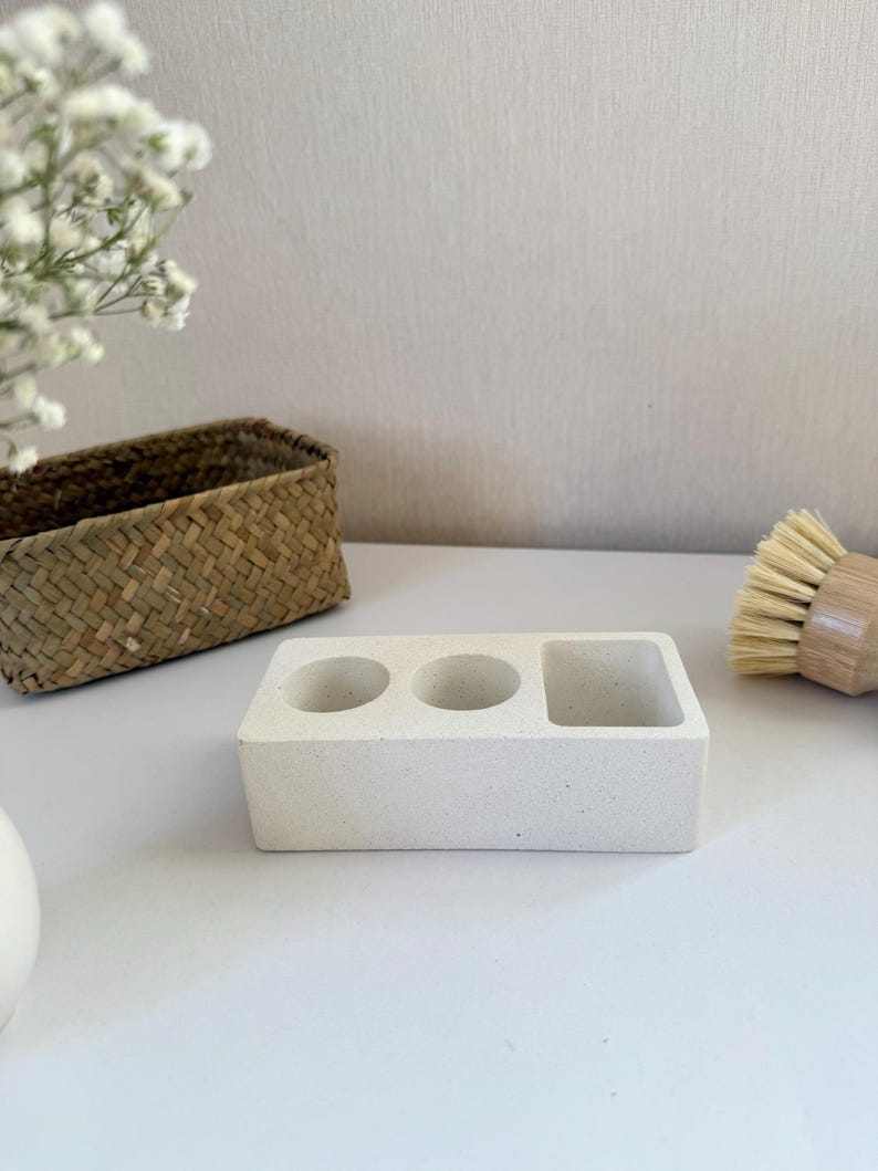 May include: White ceramic dish with three compartments, two round and one rectangular, for holding kitchen sponges or brushes.