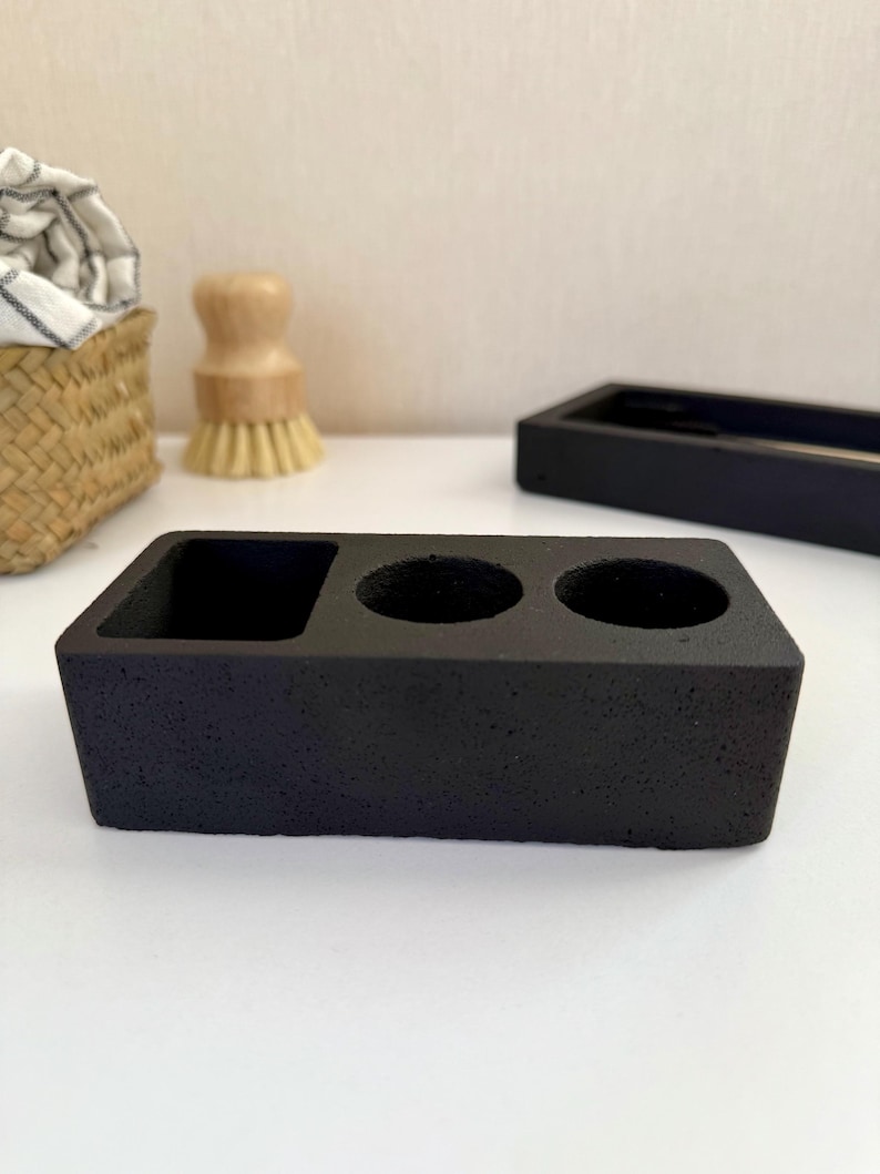 May include: Black ceramic dish with three round indentations for holding small items, such as brushes or tools.