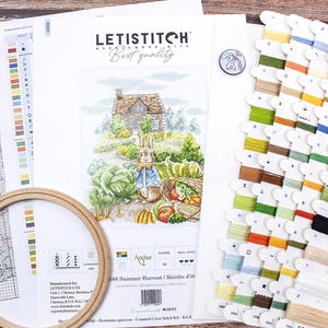 May include: A cross stitch kit featuring a colorful illustration of a rabbit in a garden with a cottage in the background. The kit includes a printed fabric, floss, and instructions. The kit is titled "Summer Harvest / R&eacute;colte d'&eacute;t&eacute;" and is made by Anchor.