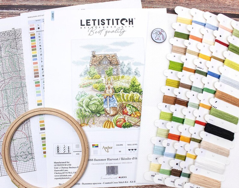 May include: A cross stitch kit featuring a colorful illustration of a rabbit in a garden with a cottage in the background. The kit includes a printed fabric, floss, and instructions. The kit is titled "Summer Harvest / R&eacute;colte d'&eacute;t&eacute;" and is made by Anchor.