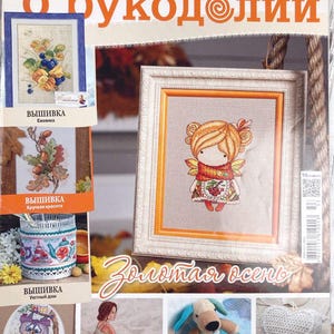 Puede incluir: Una portada de revista que presenta una variedad de proyectos de punto de cruz y ganchillo. La portada presenta a una niña con cabello rojo y una bufanda roja, una cesta de bellotas, una casita, una bailarina, un perro y un corazón. El título de la revista es "Vsyo o Rukodellii" y el texto "Zolotaya Osen" también es visible.