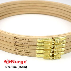 May include: Stack of wooden embroidery hoops, each 10 inches in diameter, with brass hardware. The hoops are labeled "Nurge No 6". The text "Size 10in (25cm)" is also visible.