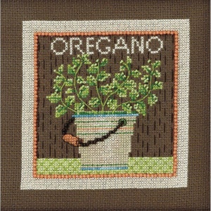May include: A cross-stitch pattern of a potted oregano plant in a white bucket with a brown handle. The plant is green and the bucket has a blue and white striped pattern. The word "OREGANO" is stitched in white letters above the plant.