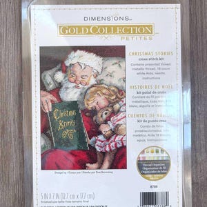 May include: A cross-stitch kit featuring a Christmas scene with Santa Claus reading to a child. The kit includes pre-sorted thread, metallic thread, an 18-count white Aida, a needle, and instructions. The finished size is 5 x 7 inches.