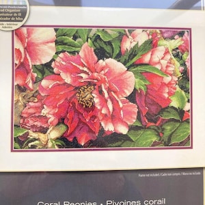 May include: A cross-stitch kit featuring a detailed floral design of coral peonies. The kit includes the text "The Gold Collection" and "Coral Peonies" with additional text in French and Spanish. The design is by Rachel Perry.