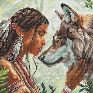 May include: A detailed cross-stitch design depicts a woman with dark hair and a wolf in a forest setting. The woman wears feathers and jewelry, gazing at the wolf. The wolf's fur is brown and gray, with a gentle expression. The background is a soft green.
