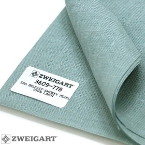 May include: A close-up of a light blue linen fabric with a white label that reads "ZWEIGART 3609-778 32ct BELFAST-SMOKEY PEARL 100% LINEN".