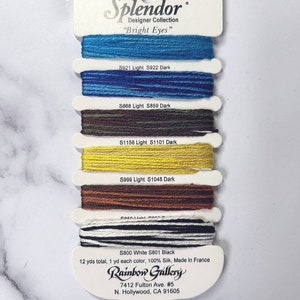 May include: A card with spools of embroidery floss in various colors, including blue, green, yellow, brown, white, and black. The card is labeled "Splendor Designer Collection "Bright Eyes" and includes the brand name "Rainbow Gallery".