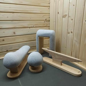 May include: Four gray and wooden tailor's ham forms for pressing and shaping fabric. The forms are made of wood with a gray fabric covering. The forms are arranged on a wooden surface.